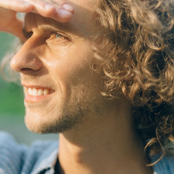 A person outdoors smiling and stretching, looking serene and healthy.